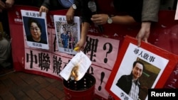 FILE - A pro-democracy activist burns a letter next to pictures of missing staff members of a publishing house and bookstore, including Gui Minhai, owner of Mighty Current, outside the Chinese liaison office in Hong Kong, Jan. 3, 2016.
