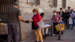 People collect food donated by volunteers and members of the Catholic Servants of Jesus congregation in Madrid, Spain, Oct. 8, 2020.