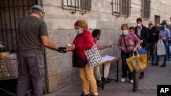 People collect food donated by volunteers and members of the Catholic Servants of Jesus congregation in Madrid, Spain, Oct. 8, 2020.