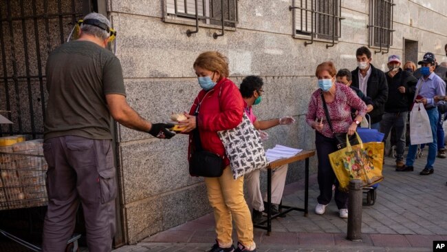 People collect food donated by volunteers and members of the Catholic Servants of Jesus congregation in Madrid, Spain, Oct. 8, 2020.