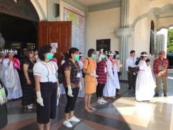 Para petugas gereja bersiap memeriksa suhu tubuh kepada umat yang hendak memasuki gedung gereja Katedral Ruteng, Nusa Tenggara Timur pada saat upacara penahbisan Uskup Ruteng, Kamis, 19 Maret 2020. (Foto: Pastor Steven Lalu)