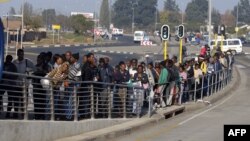 FILE - South African commuters line up at a bus stop in Soweto, May 17, 2010, during a strike by rail workers. Currently, a nationwide bus strike, in its fourth week, is causing similar lines to form for minibus taxis.