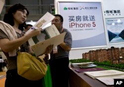 FILE - A real estate agent explains property development details to a woman during the China Property and Investment Show in Beijing.