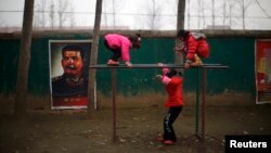 Students play next to a portrait of Soviet leader Joseph Stalin at the Democracy Elementary and Middle School in Sitong town, Henan province, China, Dec. 3, 2013.