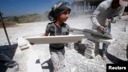 FILE - A Syrian refugee child works with his father in the south of Sidon, southern Lebanon, April 30, 2014.