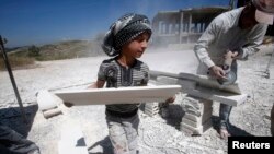 FILE - A Syrian refugee child works with his father in the south of Sidon, southern Lebanon, April 30, 2014.