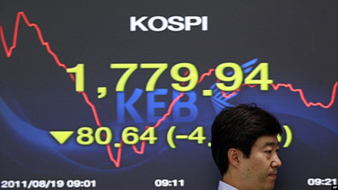 A currency trader passes by a screen showing the falling Korea Composite Stock Price Index (KOSPI) at the foreign exchange dealing room of the Korea Exchange Bank headquarters in Seoul, August 19, 2011