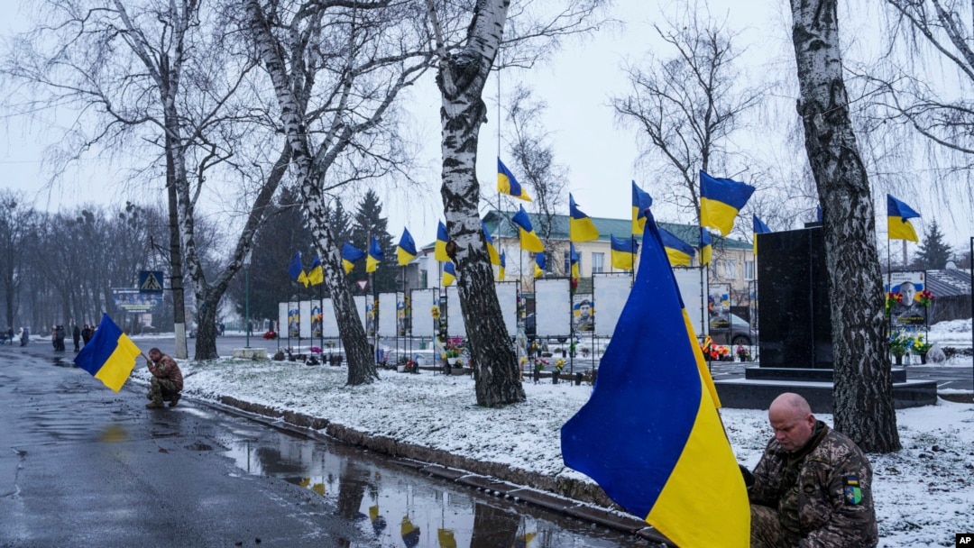 Украинские военные преклоняют колени во время церемонии в память жертв российского удара по жилому дому в Полтаве, в Дыканке, Украина, 5 февраля 2025 года. (AP Photo/Evgeniy Maloletka)