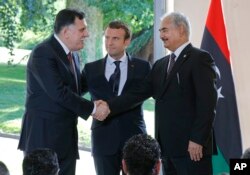 Libya's Prime Minister Fayez al-Sarraj of the U.N.-backed government (L), and General Khalifa Hifter of the Egyptian-backed commander of Libya's self-styled national army shake hands as France's President Emmanuel Macron stands between after a declaration at the Chateau of the La Celle-Saint-Cloud, west of Paris, France, July 25, 2017.