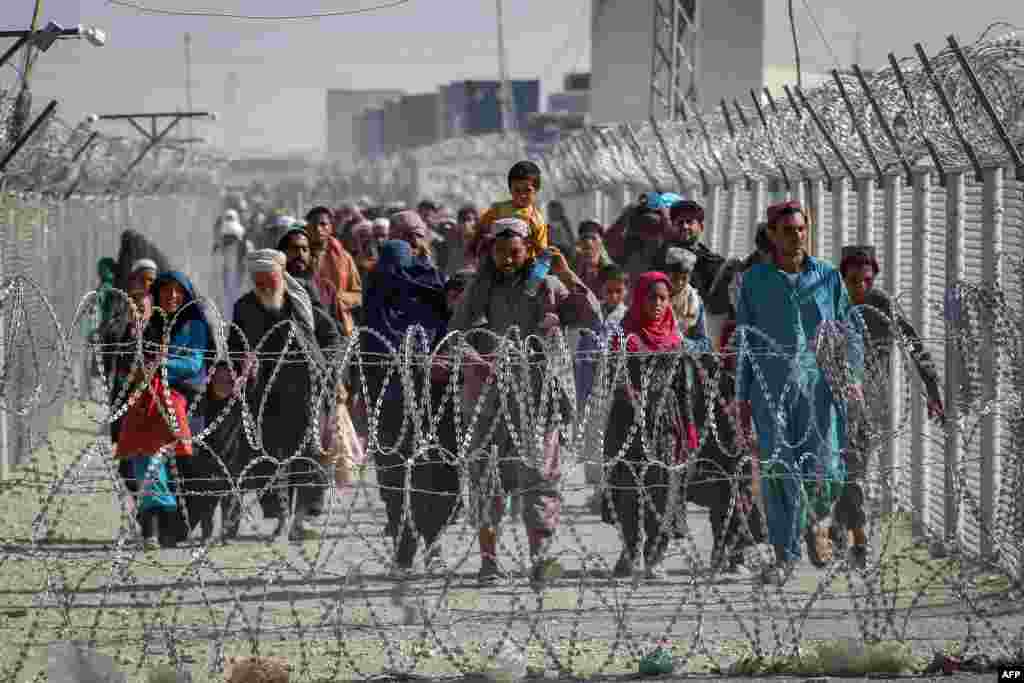 Afghans walk along fences as they arrive in Pakistan through the Pakistan-Afghanistan border crossing point in Chaman, following Taliban&#39;s military takeover of Afghanistan.