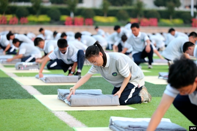 中国浙江省东阳市一所高中的学生在操场上军训时学习叠被子。（2024年8月15日）