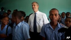 U.S. Secretary of Education Arne Duncan stands with students during his visit to Lycee de Petion-Ville high school in Petion-Ville, Haiti, Nov. 5, 2013. 