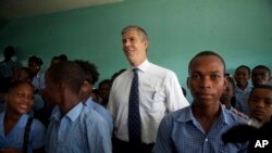 U.S. Secretary of Education Arne Duncan stands with students during his visit to Lycee de Petion-Ville high school in Petion-Ville, Haiti, Nov. 5, 2013. 