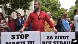 Montenegro man holds banners reading "Stop violence," left, and "For a life without fear," right, during protest in Montenegro's capital, Podgorica, on Wednesday, May 9, 2018. 