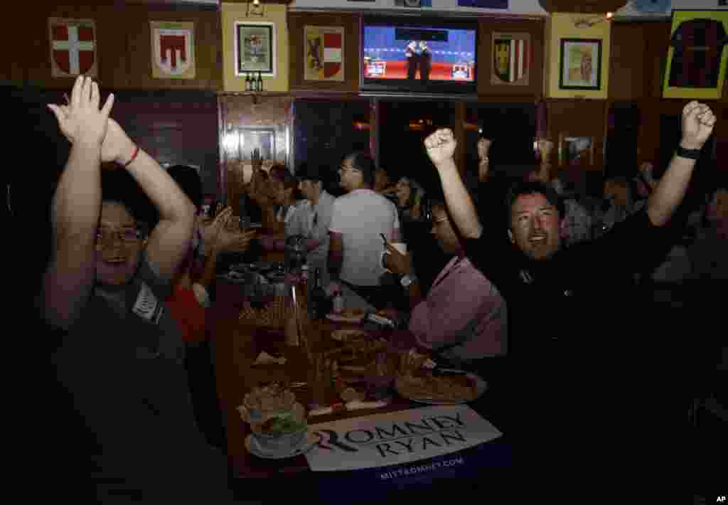 Mariella Roque, 21, of Miami, left, and Jorge Palamino, 24, of Miami, right, supporters of Republican presidential candidate Mitt Romney, cheer as they watch a televised debate between Romney and President Barack Obama in Coral Gables, Florida.