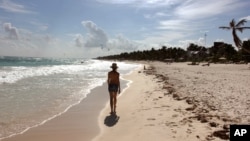 A woman walks along the beach in Tulum, Mexico.