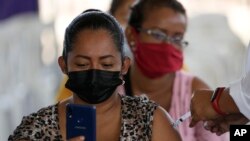 Una mujer graba con su celular mientras es vacunada con una dosis de la vacuna Sinovac COVID-19 en Guayaquil, Ecuador, jueves 22 de julio de 2021