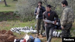 Rebel fighters from the Suqour al-Sham Brigade carry mortar shells to be launched toward forces loyal to Syria's President Bashar al-Assad near Idlib, March 19, 2015. 