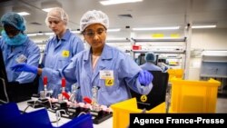 FILE - Employees work on the production line of a COVID-19 coronavirus home test unit, at the production facility of Australian digital diagnostics company Ellume in Brisbane, Dec. 21, 2020.