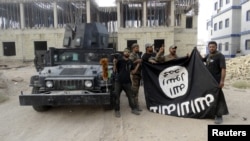 FILE - Iraqi security forces hold an Islamist State flag which they pulled down at the University of Anbar, in Anbar province July 26, 2015.