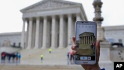 FILE - A Supreme Court visitor takes pictures with her cell phone outside the Supreme Court in Washington.