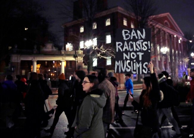 FILE - Several hundred people march past the gates of Harvard Yard at Harvard University while protesting the travel ban in Cambridge, Mass., March 7, 2017.