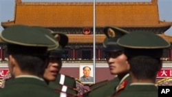 Paramilitary policemen look back while patrolling on the Tiananmen Square in front of the late communist leader Mao Zedong's portrait in Beijing, China, 15 Oct. 2010