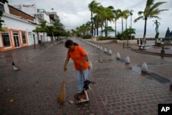 A city cleaner sweeps normal leaves and debris from a seafront walkway, the morning after Hurricane Patricia passed further south sparing Puerto Vallarta, Mexico, Oct. 24, 2015.