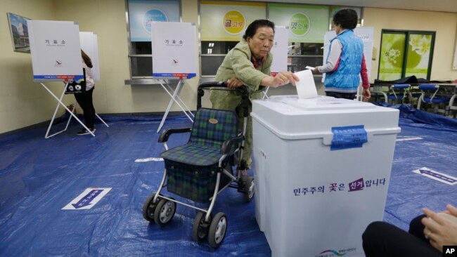 FILE - A woman casts her ballot for presidential election at a polling station in Seoul, South Korea, May 9, 2017.