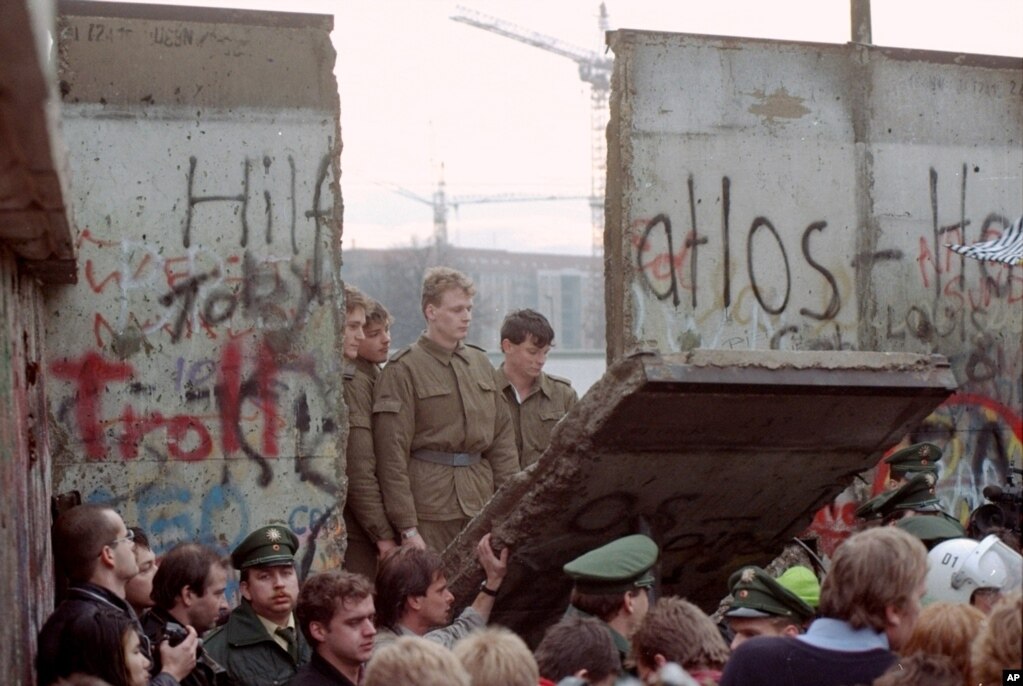 و بخشی از دیوار برلین که مقابل دروازه براندنبورگ جدا شد. سربازان آلمان شرقی در آن‌سوی دیوار نظاره‌گر برچیده شدن دیوار بودند