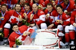 Canada players pose for pictures after they beat Sweden 3-0 in the men's ice hockey gold medal game at the 2014 Winter Olympics, Feb. 23, 2014, in Sochi, Russia.