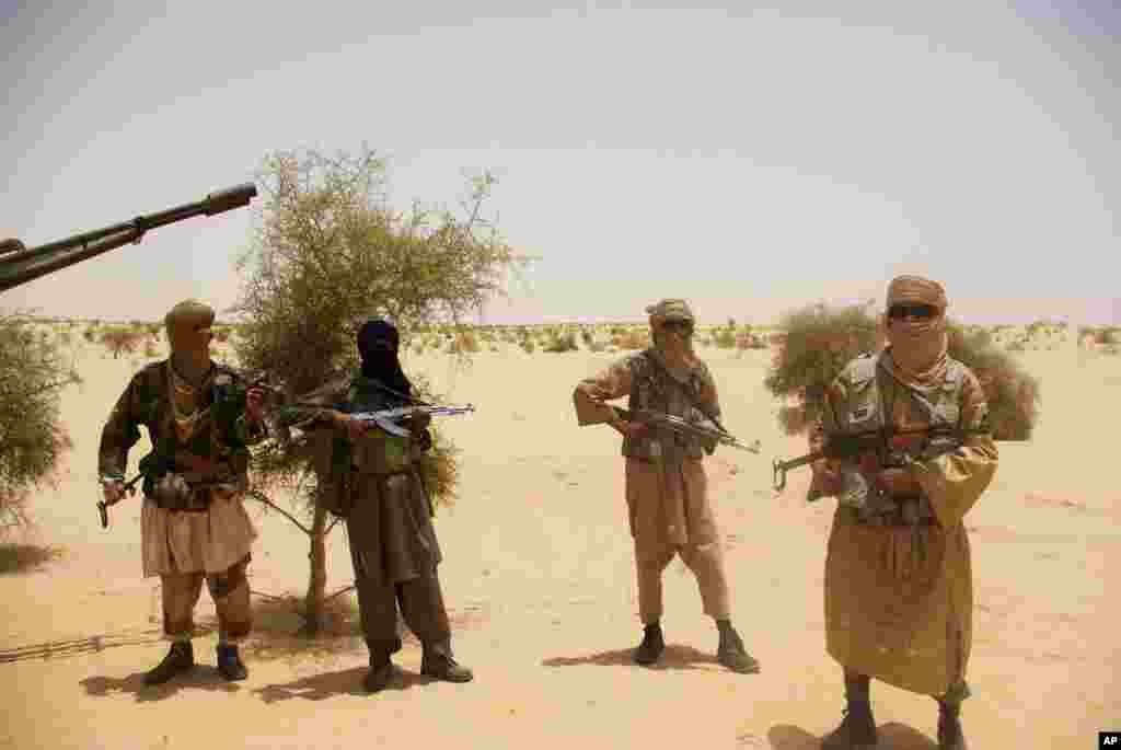Fighters from Islamist group Ansar Dine stand guard as they prepare to hand over a Swiss female hostage in the desert outside Timbuktu, Mali, April 24, 2012.