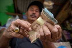 Seorang penjual makanan ringan menghitung uang hasil penjualannya, Jakarta, 20 Februari 2020. (Foto: AFP)