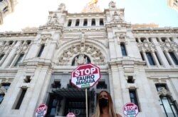 Seorang pendukung hak-hak hewan, mengenakan masker, berdiri di antara tanda-tanda bertuliskan: "Hentikan adu banteng" dalam aksi protes menuntut pelarangan adu banteng, di Madrid, Spanyol 12 Juli 2020. (REUTERS / Sergio Perez)
