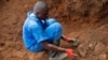 Un travailleur burundais de la Commission de vérité et réconciliation extrait le crâne d'une personne non identifiée d'un charnier sur la colline de Bukirasazi dans la province de Karusi, au Burundi, le 27 janvier 2020.