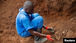 Mfanyakazi wa Burundi kutoka katika Kamisheni ya Ukweli na Suluhu akitoa fuvu la mtu aliyekuwa hajatambulikana kutoka katika kaburi la watu waliozikwa pamoja nchini humo. REUTERS/Evrard Ngendakumana - RC21PE9DJA9D