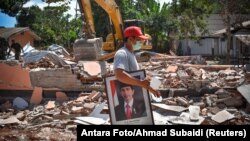 지난 12일 롬복 섬 지진 현장에서 한 남성이 인도네시아 대통령 사진을 옮기고 있다. 
