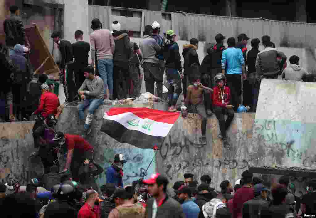 بغداد میں مظاہرین احتجاج کے دوران عراقی پرچم اٹھائے ہوئے ہیں۔&nbsp; 