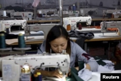 FILE - A woman works in a small-sized factory producing clothes and hats, in which more than half of its production line has stopped its operation because of a downturn in its business at the Qingyundian industrial zone in Beijing, Oct. 19, 2015.