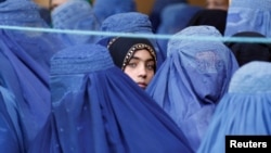 A girl looks on among Afghan women lining up to receive relief assistance in Jalalabad, Afghanistan, June 11, 2017. In Afghanistan, openly using a woman's name is taboo, but a social media campaign is starting to challenge that.