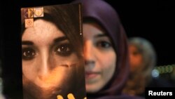A Libyan woman holds a pamphlet, which reads "Together to end the violence against women" during a gathering in Benghazi Nov. 25, 2012. 