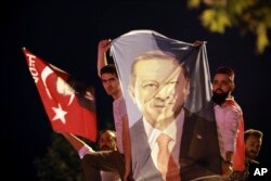 Men, holding a banner with a picture of Turkey's President Recep Tayyip Erdogan, celebrate outside his Justice and Development Party, or AKP, headquarters in Istanbul, June 24, 2018.