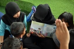 Seorang relawan membacakan buku untuk anak-anak jalanan yang tinggal di bawah jembatan di Jakarta. (Foto ilustrasi: AFP/Adek Berry)