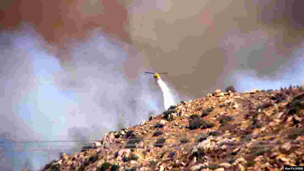 直升機在山區噴灑滅火劑（美國之音國符拍攝）