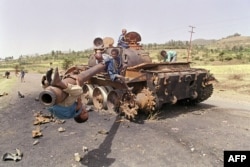 FILE - Eritrean children play on an Ethiopian army tank, June 7, 1991. The tank was destroyed by Eritrean People’s Liberation Front (EPLF) rebels in the battle for Asmara, capital of Eritrea, that fell days earlier to EPLF rebels after 17 years of war.
