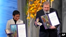 Nobel Peace Prize winners Dmitry Muratov from Russia and Maria Ressa of the Philippines pose with their awards during the Nobel Peace Prize ceremony at Oslo City Hall, Norway, Dec. 10, 2021.