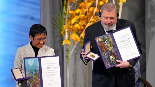 Nobel Peace Prize winners Dmitry Muratov from Russia and Maria Ressa of the Philippines pose with their awards during the Nobel Peace Prize ceremony at Oslo City Hall, Norway, Dec. 10, 2021.