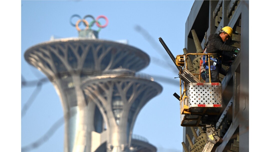 Seorang pria bekerja di dekat Menara Olimpiade di Beijing, 4 Januari 2022. Beijing akan menjadi tuan rumah Olimpiade Musim Dingin 2022, yang akam dimulai 4 Februari 2022 mendatang. (Noel Celis / AFP)