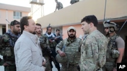FILE - Kunduz chief of police, Mohammad Qasim Jangalbagh, left, talks to U.S. and Afghan special forces in Kunduz city, north of Kabul, Afghanistan, Oct. 1, 2015. 