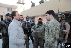 FILE - Kunduz chief of police, Mohammad Qasim Jangalbagh, left, talks to U.S. and Afghan special forces in Kunduz city, north of Kabul, Afghanistan, Oct. 1, 2015.